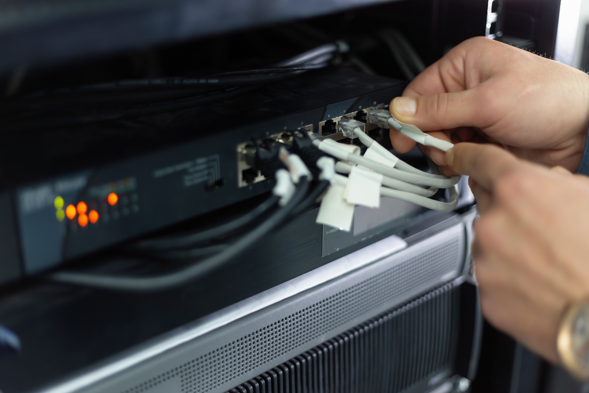 Network engineer connecting ethernet cable to router in server room